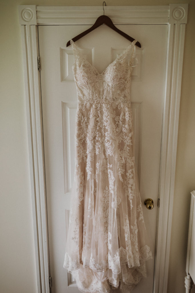 Lace wedding dress hanging on door