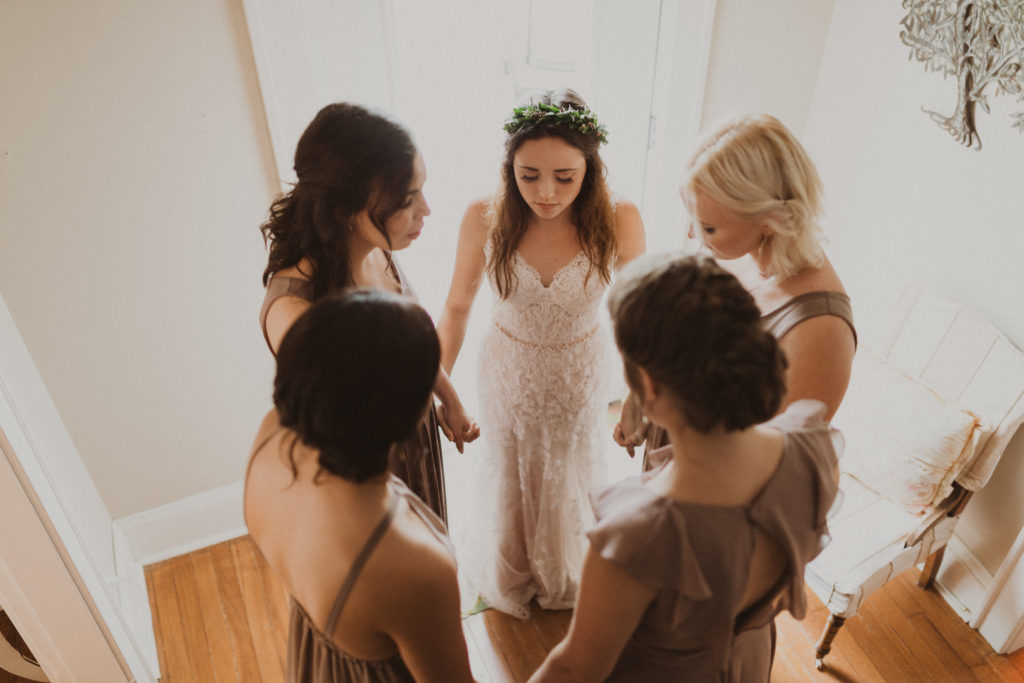 bride praying with bridesmaids before wedding