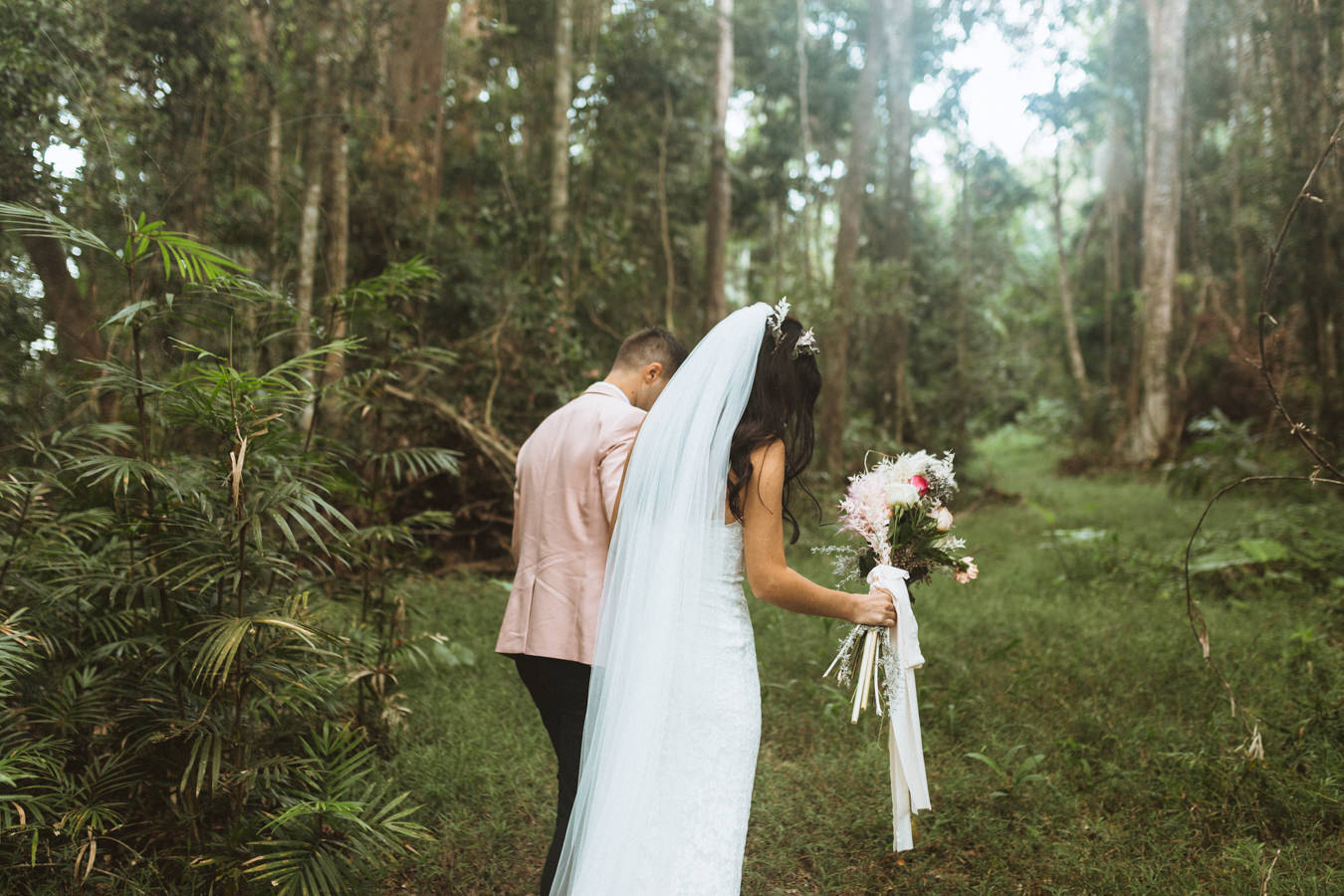 bride and groom walking through rainforest