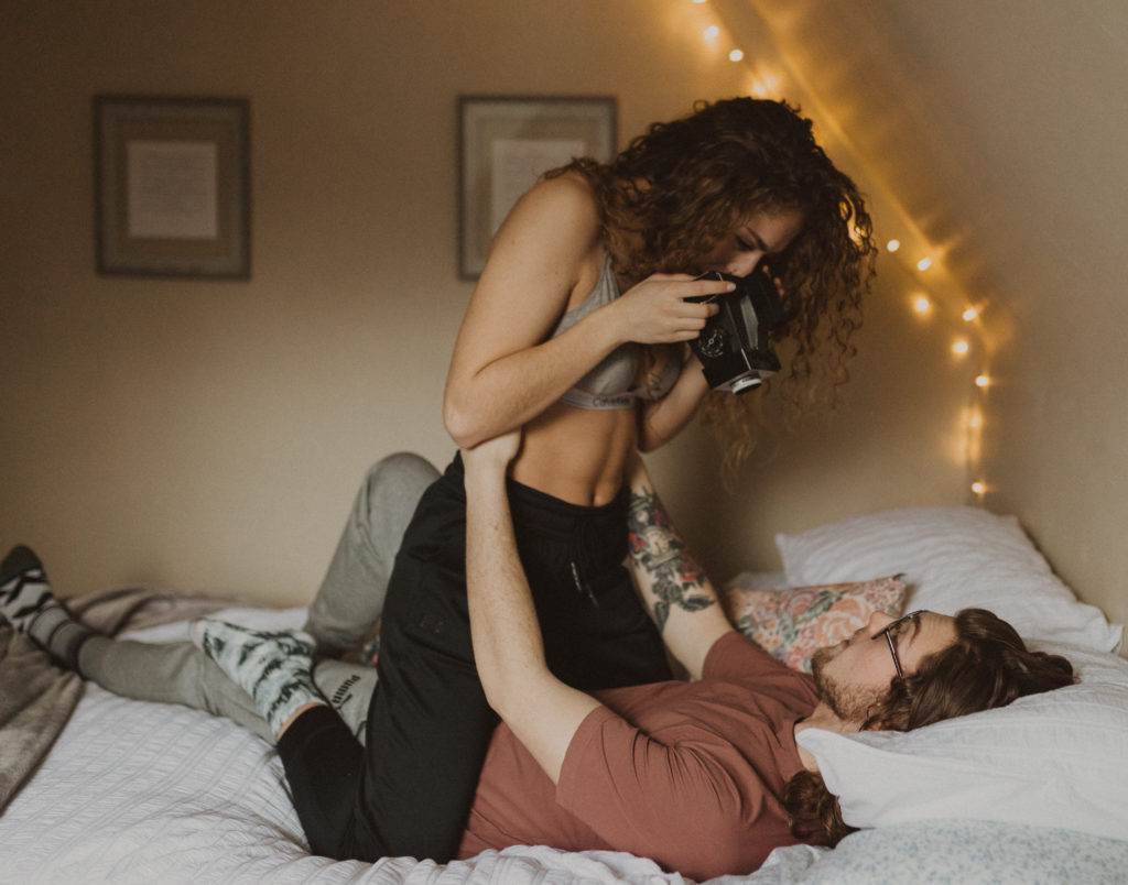 couple taking polaroid pictures of each other in bed