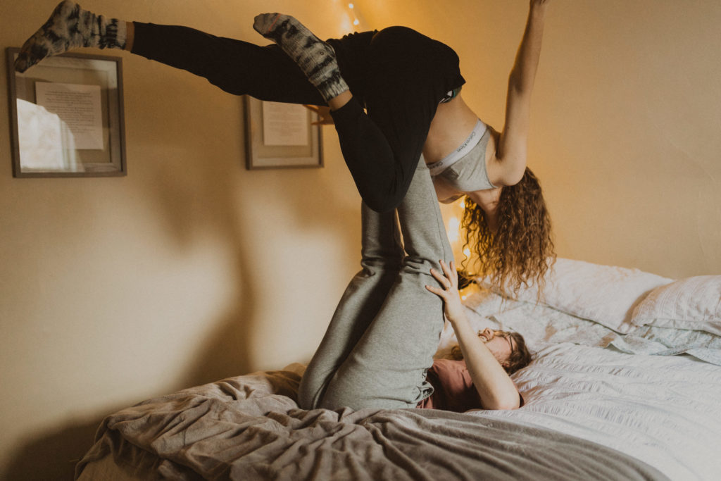 playful couple having airplanes in bed during their in-home photography session