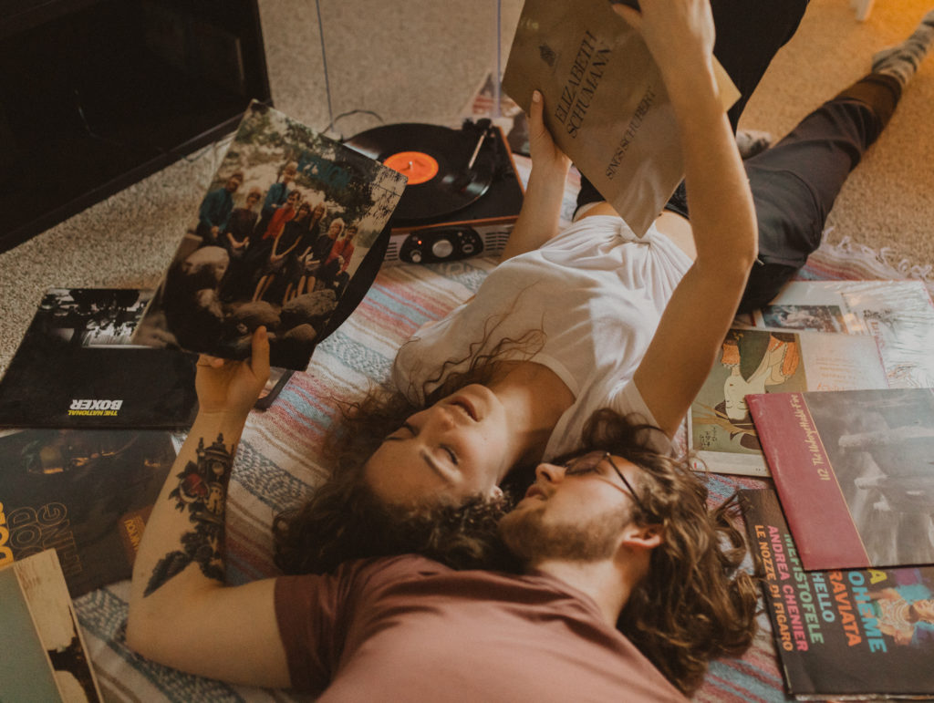 couple laying on living room floor looking through old records 
