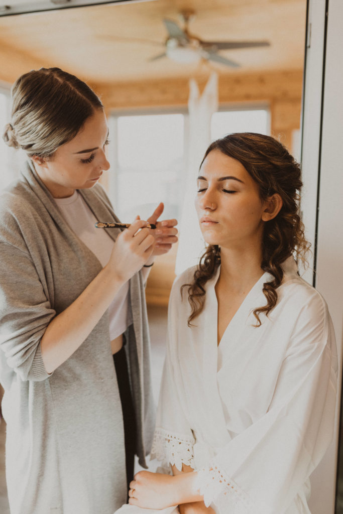 Bride getting makeup done on wedding day