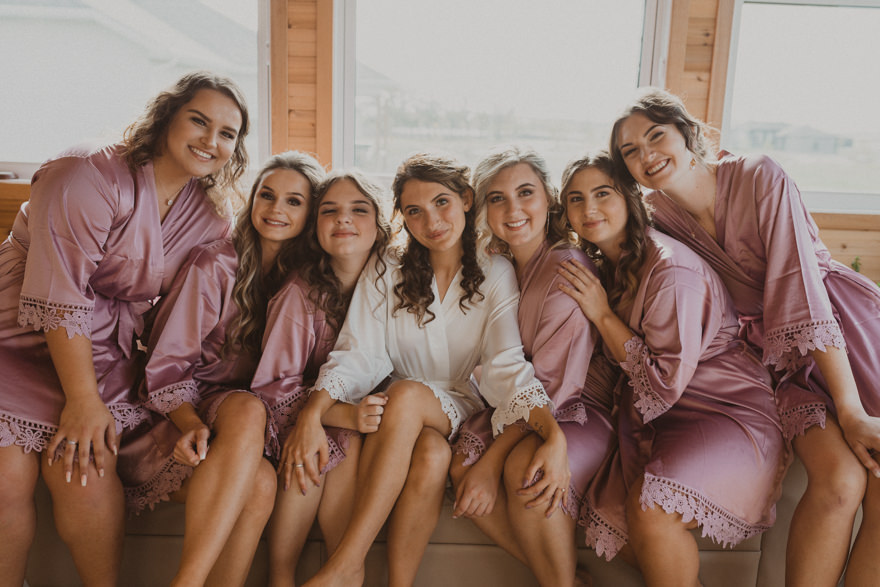 bride and bridesmaids getting ready on morning of wedding wearing matching purple robes