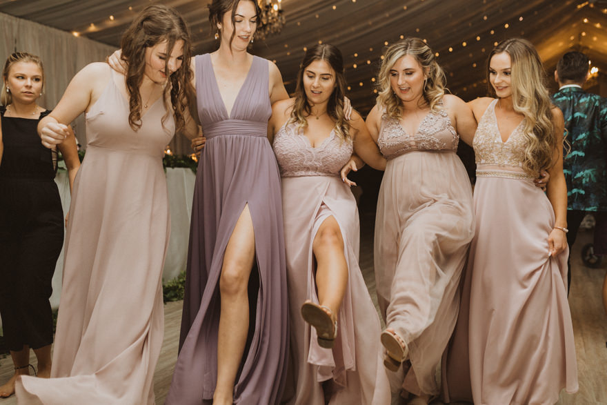 bridesmaids dancing at wedding reception in mix matched purple and tan dresses