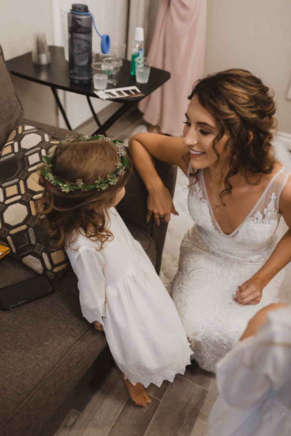 bride talking to flower girl while getting ready