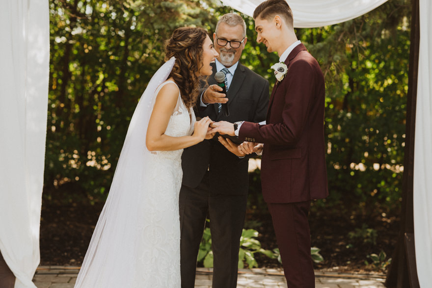 bride and groom exchange rings during wedding ceremony in Winnipeg