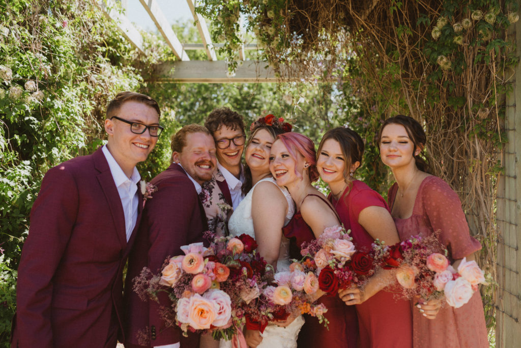 colourful bridal party, bridesmaids wearing mismatched pink dresses and groomsmen wearing maroon suits