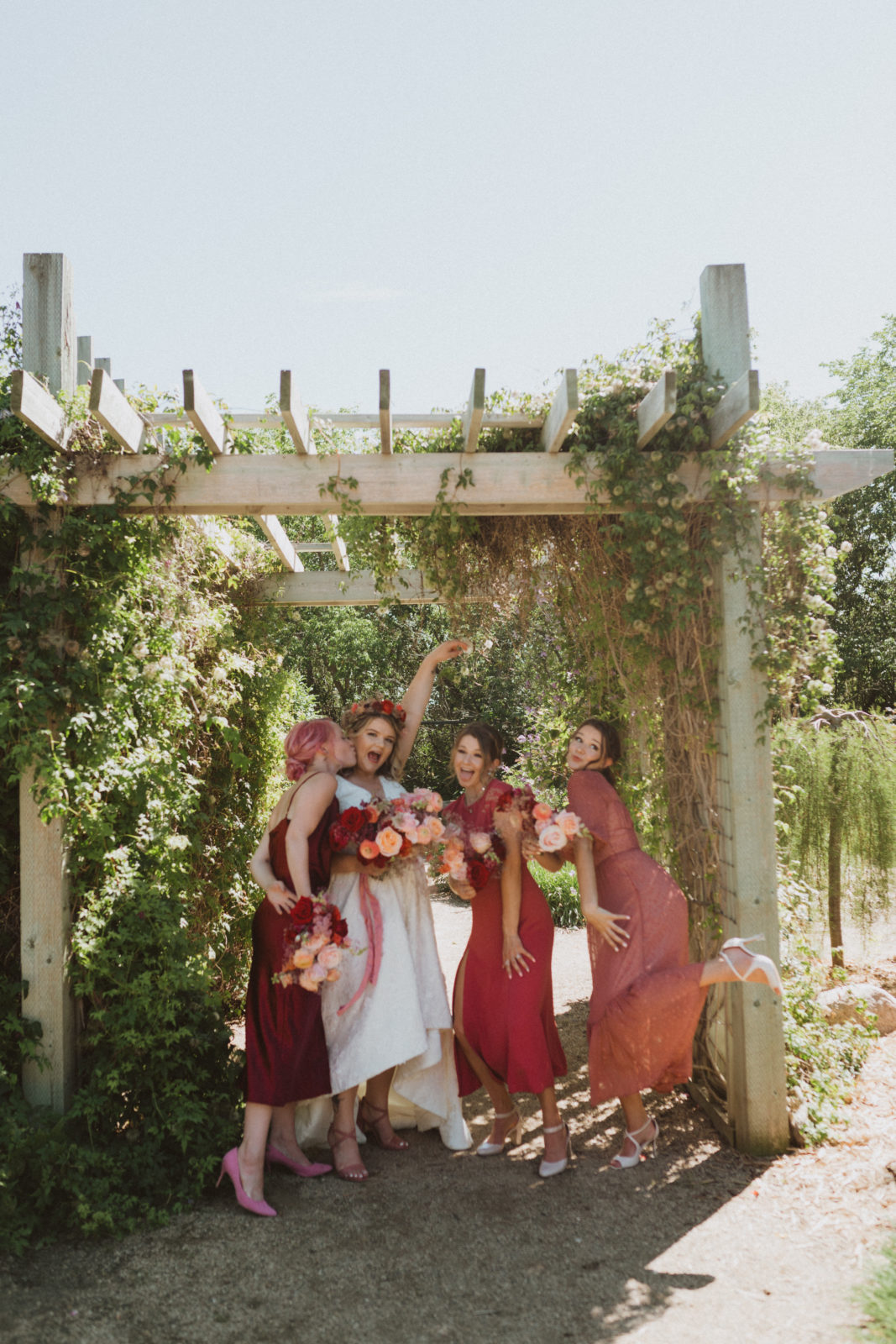pink mismatched bridesmaids dresses with colourful red bouquets