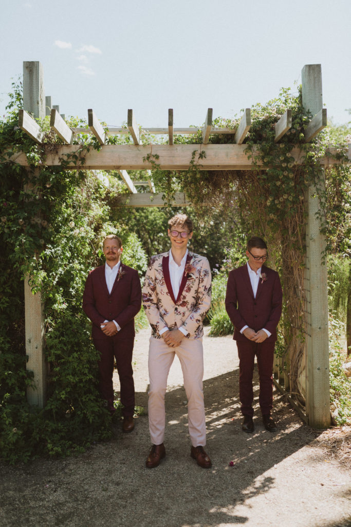 groomsmen wearing burgundy suits and groom wearing floral tux
