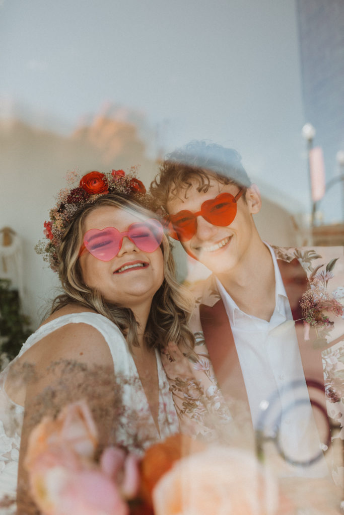 bride and groom wearing neon heart glasses