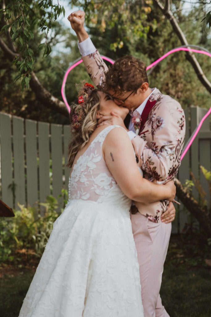 bride and groom first kiss, stylish colourful backyard wedding