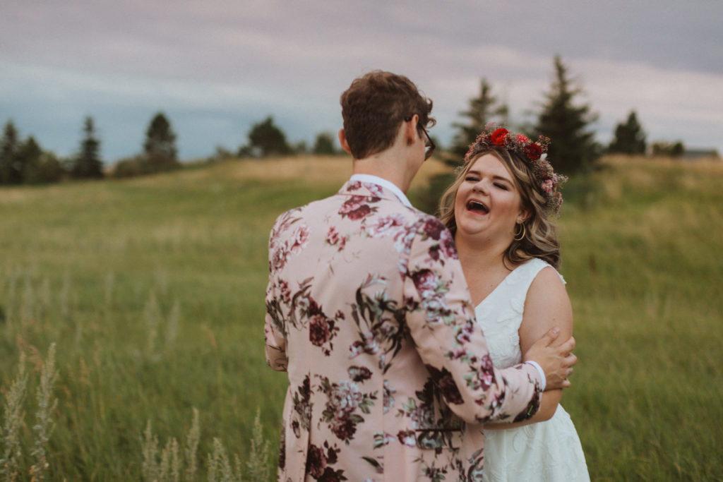 groom in floral suit from asos, bride in BHLDN dress from Blush and Raven YYC holding colourful bouquet and wearing a flower crown of dried flowers