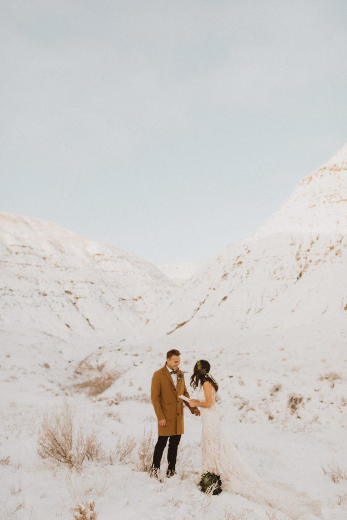 Intimate winter elopement ceremony in Drumheller, Alberta with no guest. Couple is reading their vows in private.