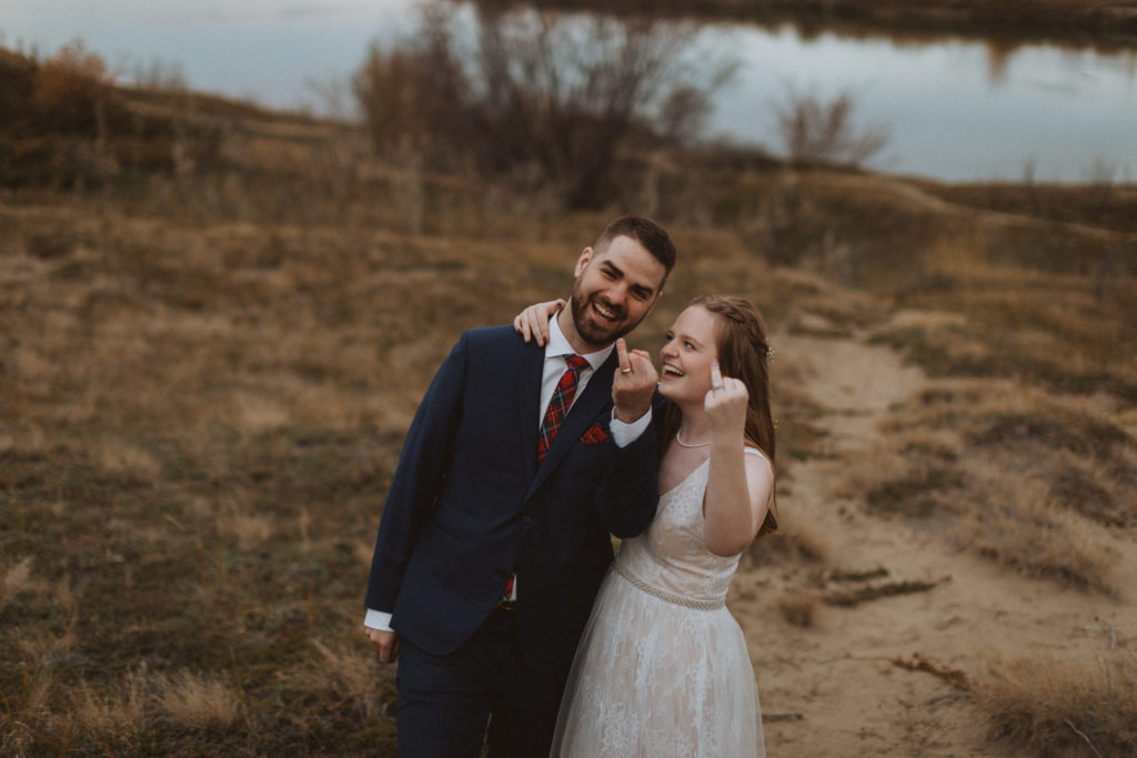 couple elopes in Saskatchewan, photo of them flipping off the camera with their ring fingers. Advice on should you elope with family or alone?

