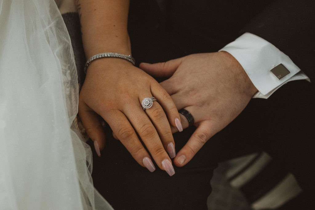 Wedding rings portrait, bride has gel nails and groom is wearing a square cufflink.