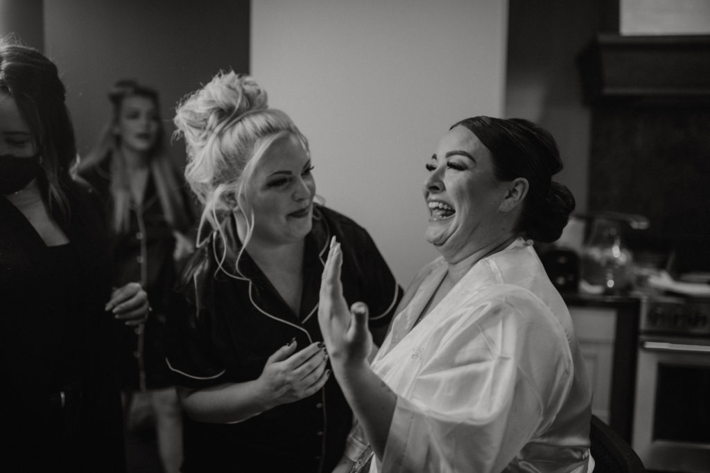 Bride getting ready with mom and friend the morning of her elopement day. Crying while getting her makeup done. Black and white picture