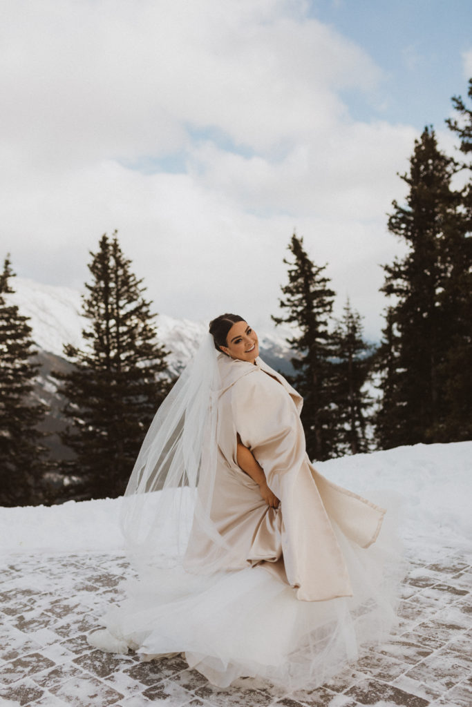 Portrait of bride from Banff Gondola Elopement. Twirling around in her lace ballgown wedding dress and silk shawl to stay warm.