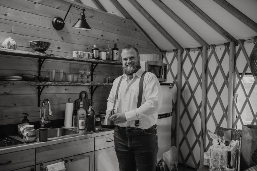 Groomsman getting ready inside a yurt at Flora Bora for Saskatchewan elopement. Black and white photography.