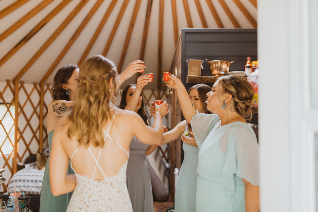 Bride celebrates with shots on elopement day with bridesmaids before walking down the aisle.