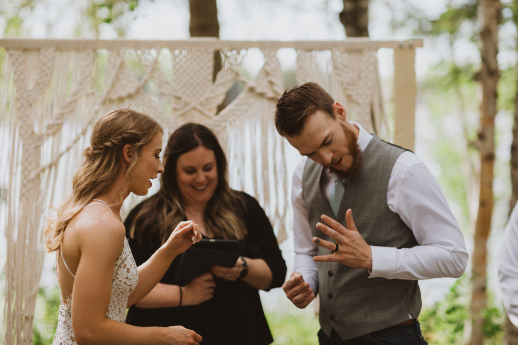 Groom showing off his new ring during elopement ceremony. Beautiful macrame arbor as the backdrop for their ceremony design. Saskatchewan elopement photographer
