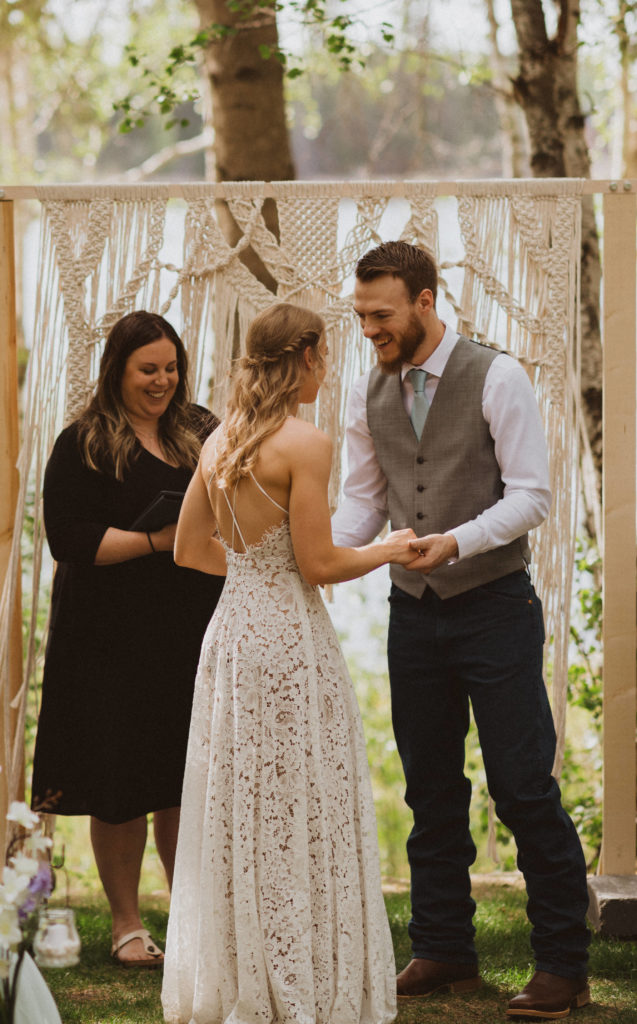 Those we just got married look. Wedding ceremony at flora bora with only 10 guests. Beautiful handmade macrame arbor. Lace wedding dress from lulus and grey vest with a blue tie.