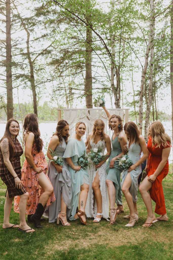 All the girls from wedding showing off their slit in their dresses. Elopement guest portraits. Flora Bora Yurt Elopement. Wedding party portraits. Bridesmaids wearing mismatched blue bridesmaid dresses with bride in a lace wedding dress from Lulus. Groomsmen wore jeans, cowboy boots, and suspenders from Lamlees. Saskatchewan elopement photographer. Creative bridal party photo ideas.
