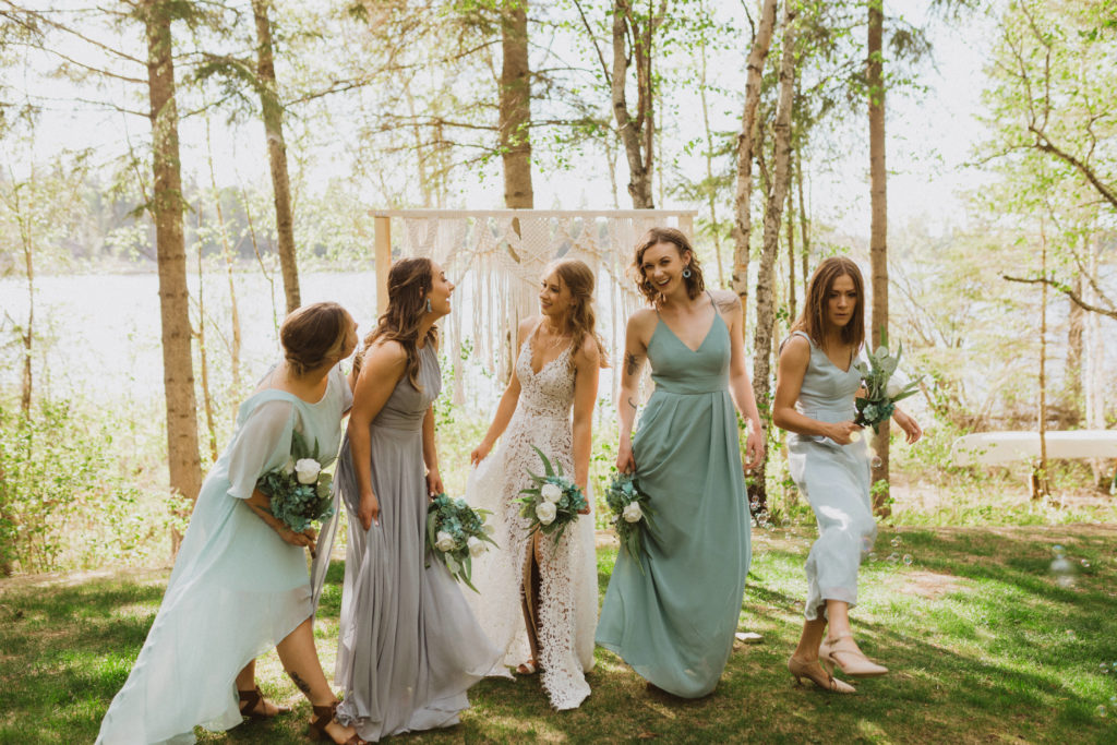 Flora Bora Yurt Elopement. Wedding party portraits. Bridesmaids wearing mismatched blue bridesmaid dresses with bride in a lace wedding dress from Lulus. Groomsmen wore jeans, cowboy boots, and suspenders from Lamlees. Saskatchewan elopement photographer. Creative bridal party photo ideas.