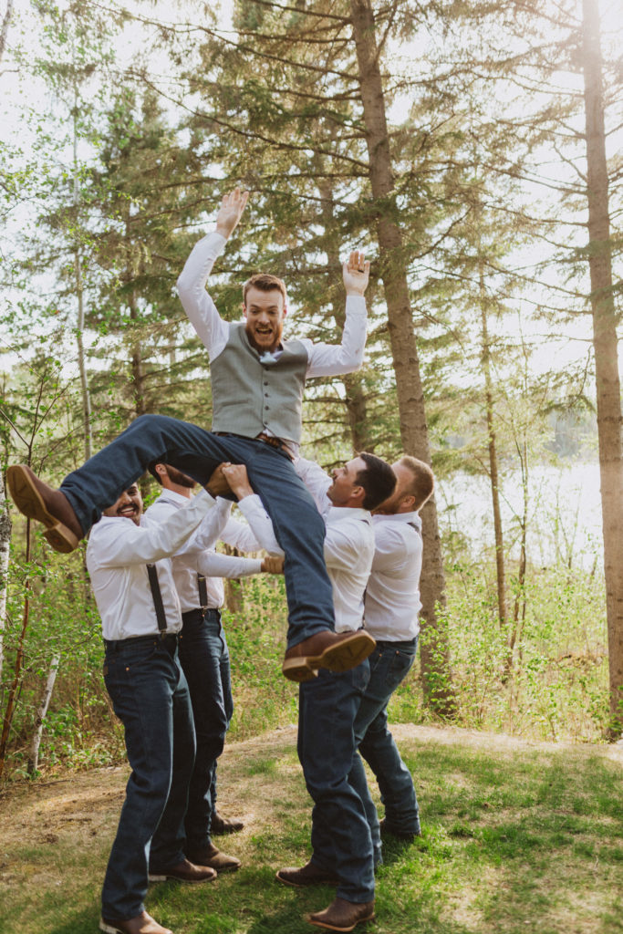 Groomsmen throwing groom in the air. Wedding party photos. Saskatchwan intimate wedding photographer