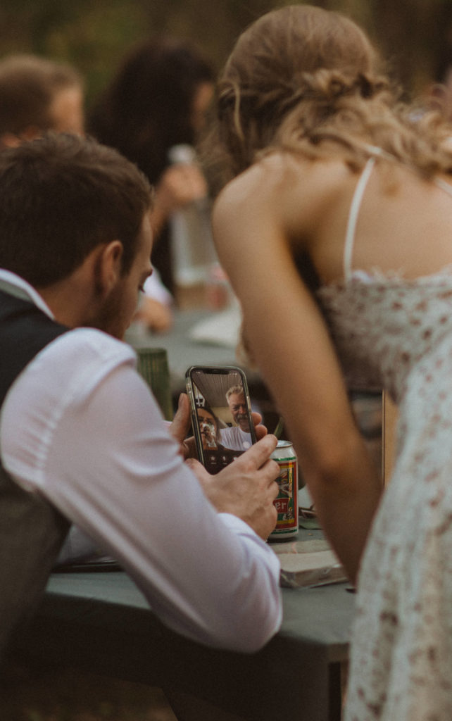 bride and groom facetiming parents during reception dinner.