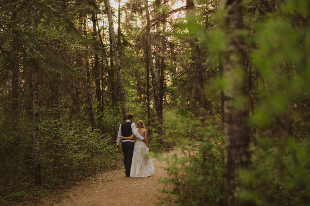Flora Bora yurt elopement in the forest. Bride and Groom wedding portraits. Posing ideas. Couple photos by Liv Hettinga Photography a Saskatchewan elopement photographer. Couple walking through the woods.