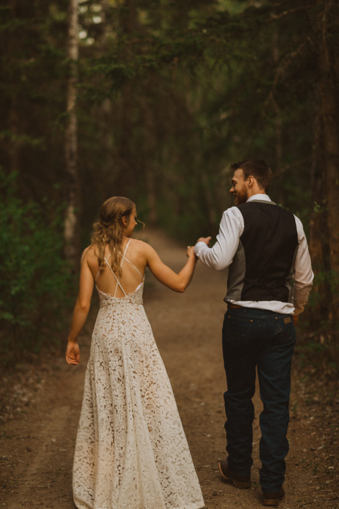 Flora Bora yurt elopement in the forest. Bride and Groom wedding portraits. Posing ideas. Couple photos by Liv Hettinga Photography a Saskatchewan elopement photographer. Couple walking through the trees.
