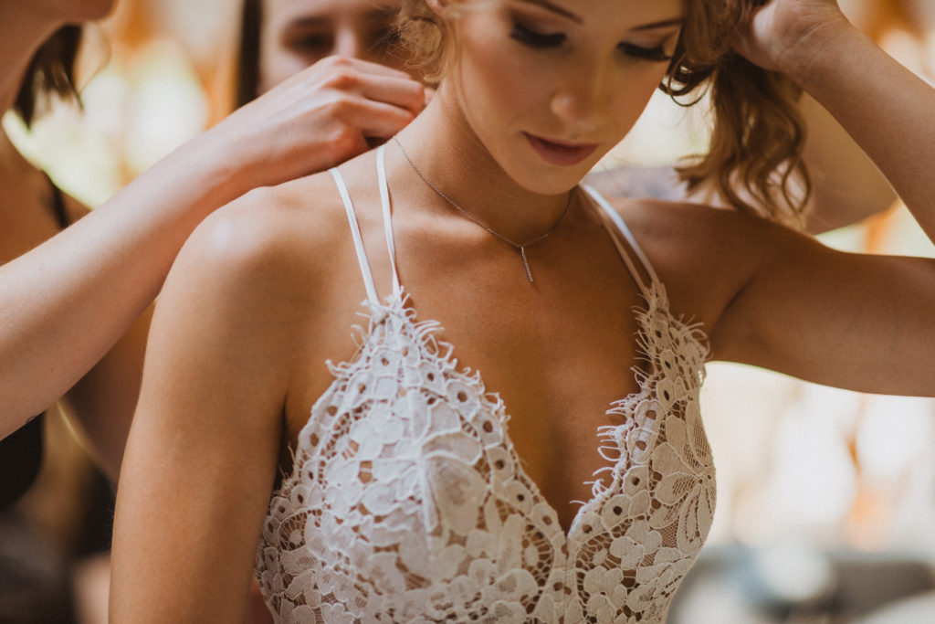 Bride getting ready photos. Putting on necklace. Lace wedding dress from Lulus.