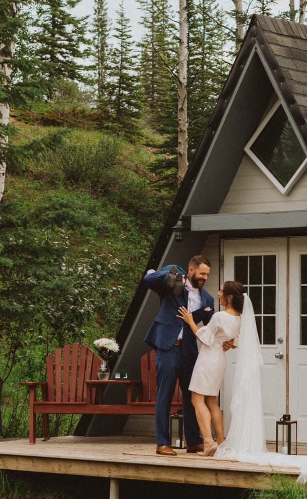 Post ceremony bliss! The groom slings his son over his shoulder and laughs with his bride at their Alberta cabin elopement. 