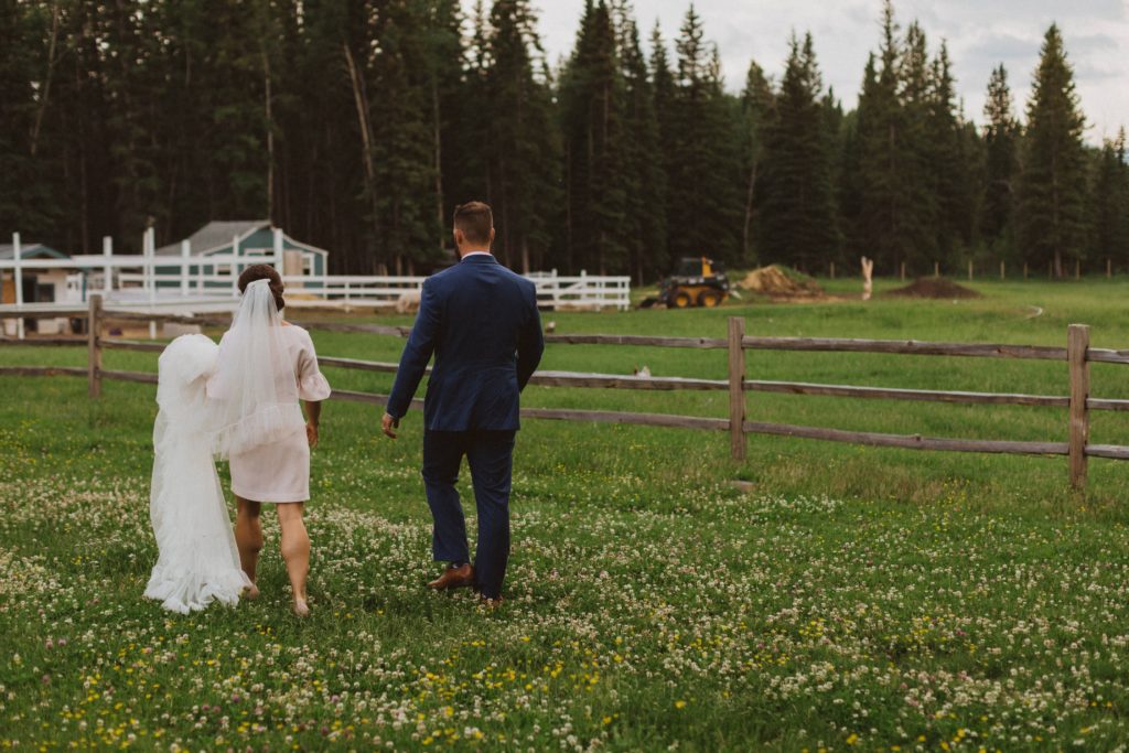 The newlywed couple walks through a pasture together after saying their vows for portrait photos with Liv Hettinga Photography. 