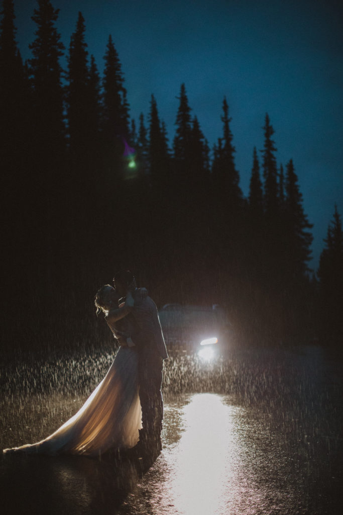 elopement first dance in the rain lit by the headlights on their car