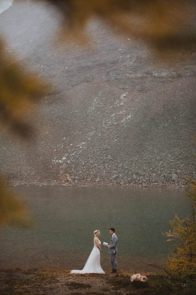 couple elopes at glacier lake along larch valley hike surrounded by the golden larches

