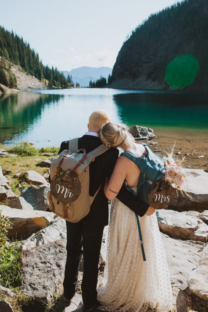 lake louise hiking elopement. Couple wearing backpacks and wooden Mr and Mrs signs