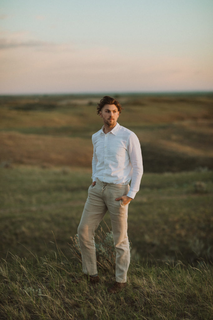 groom portraits in Saskatchewan sand dunes wearing tan linen dress pants and a white linen shirt