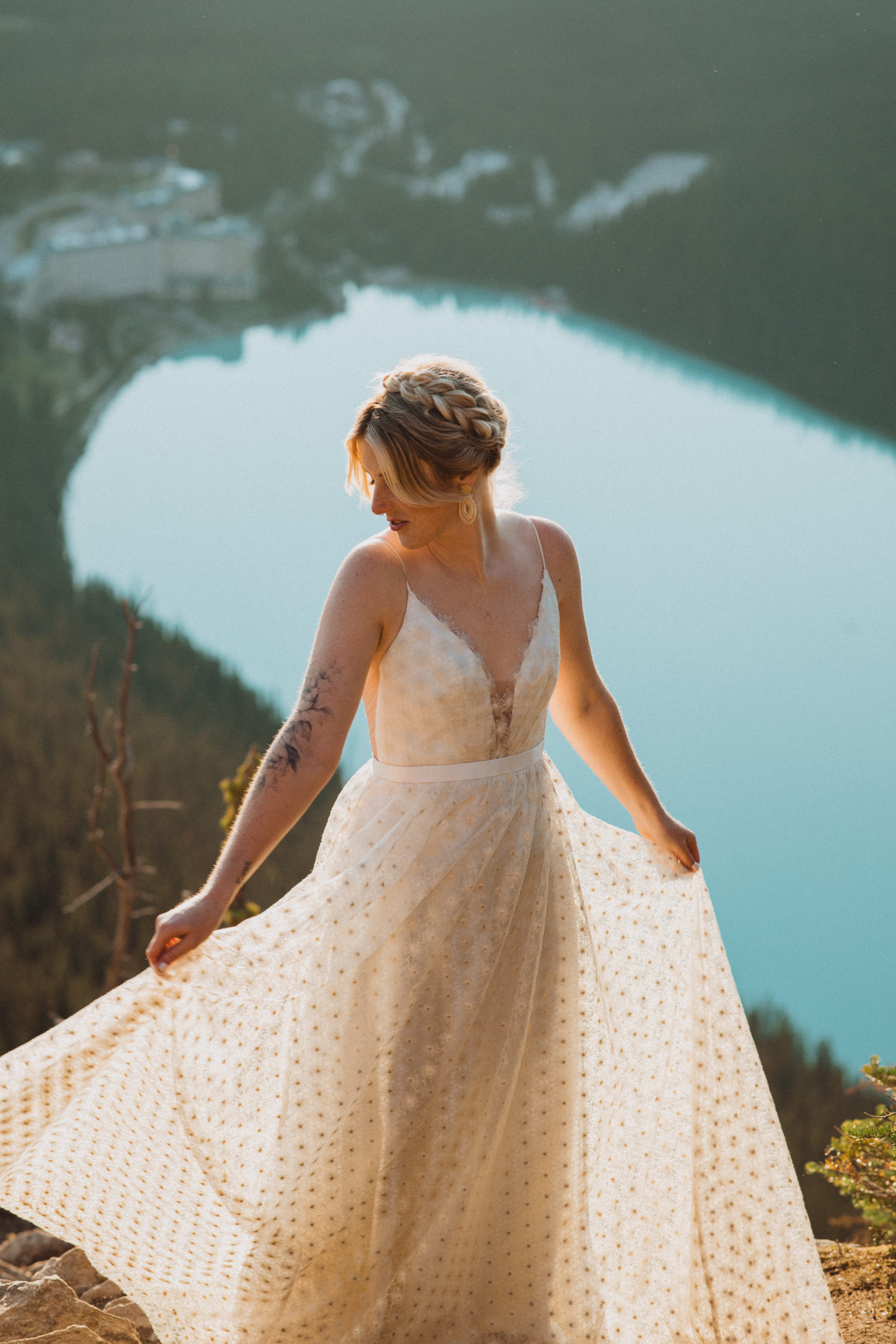 bride in wedding dress from Love Note Bride on top of mountain overlooking Lake Louise in Banff National Park