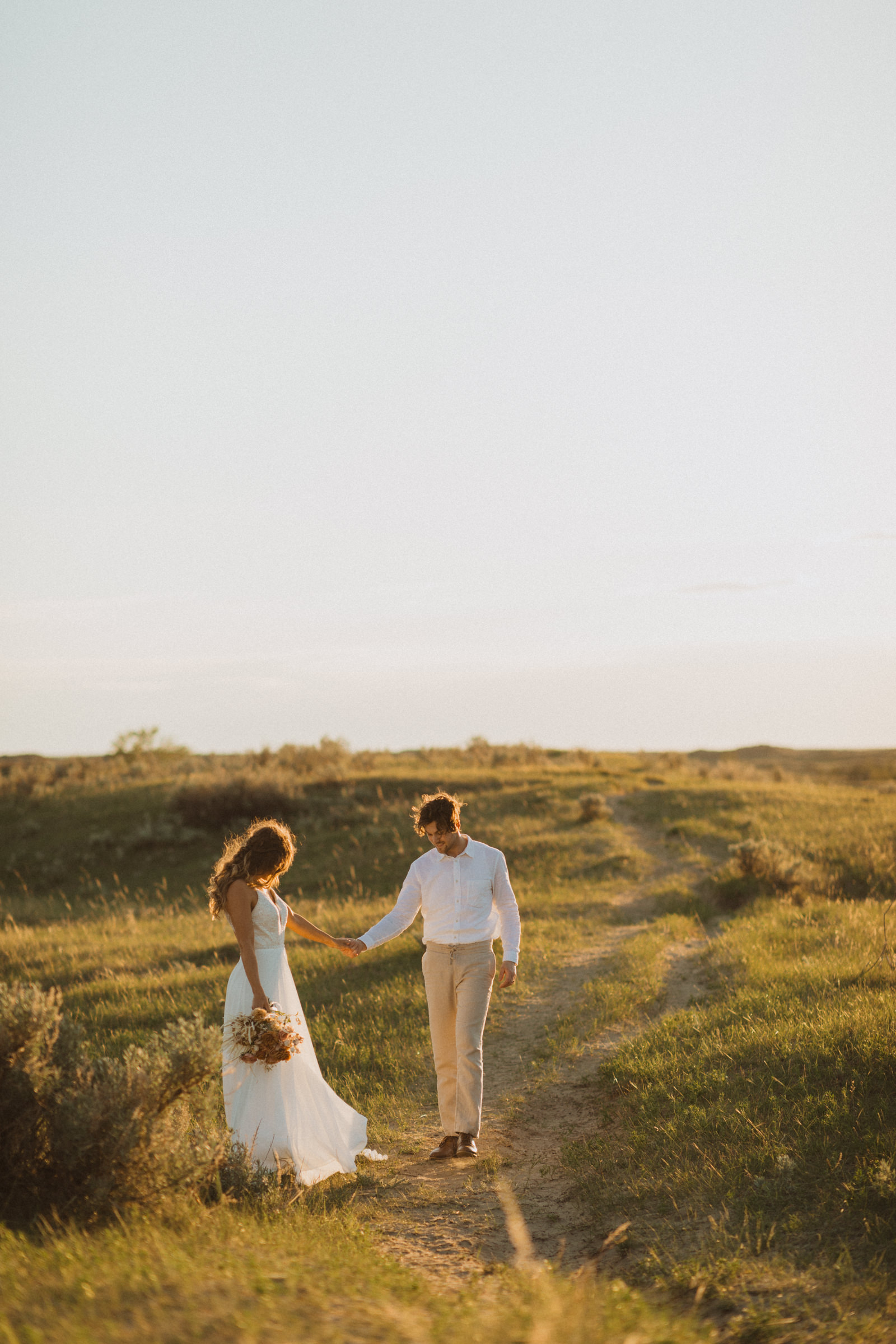 groom admiring his bride. boho wedding dress from exquisite and linen suit