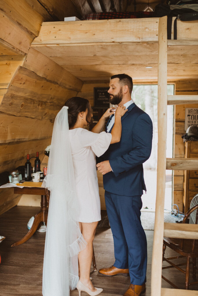 bride and groom getting ready together in cabin airbnb in Alberta