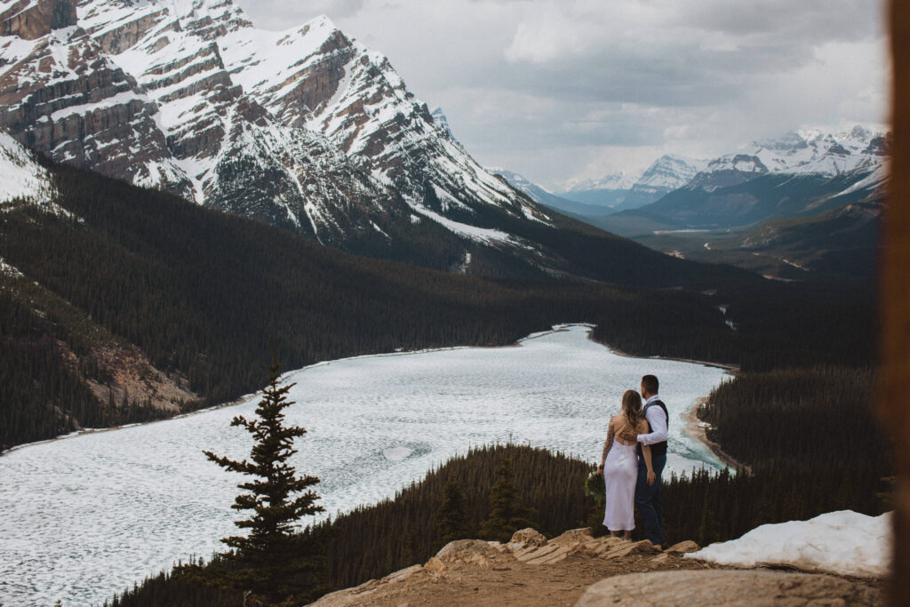 couple hiked up to Peyto Lake Viewpoint in spring as lake just begins to thaw