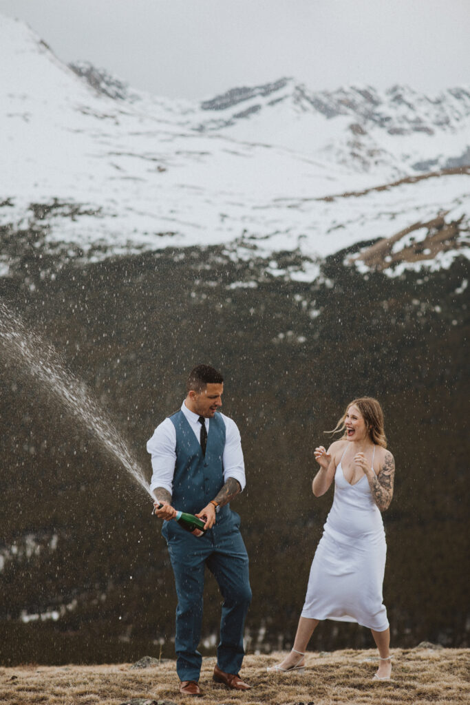 couple celebrates their elopement by popping a bottle of champagne